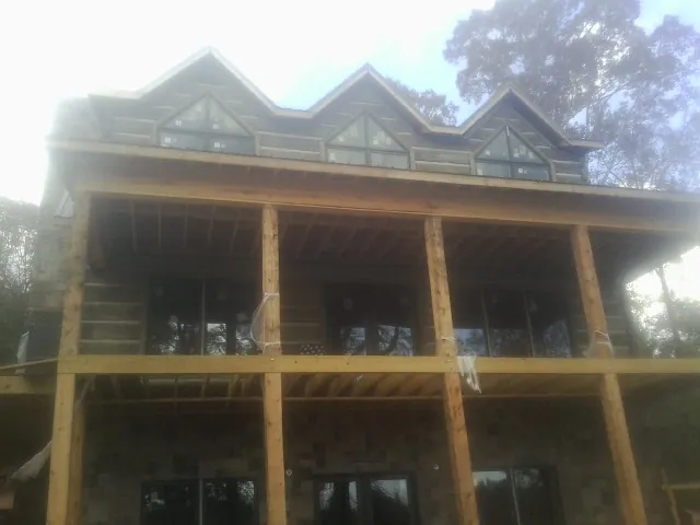 Dormers and porch framing on a large log home under construction — Roof Coating work by our crew in Mercer