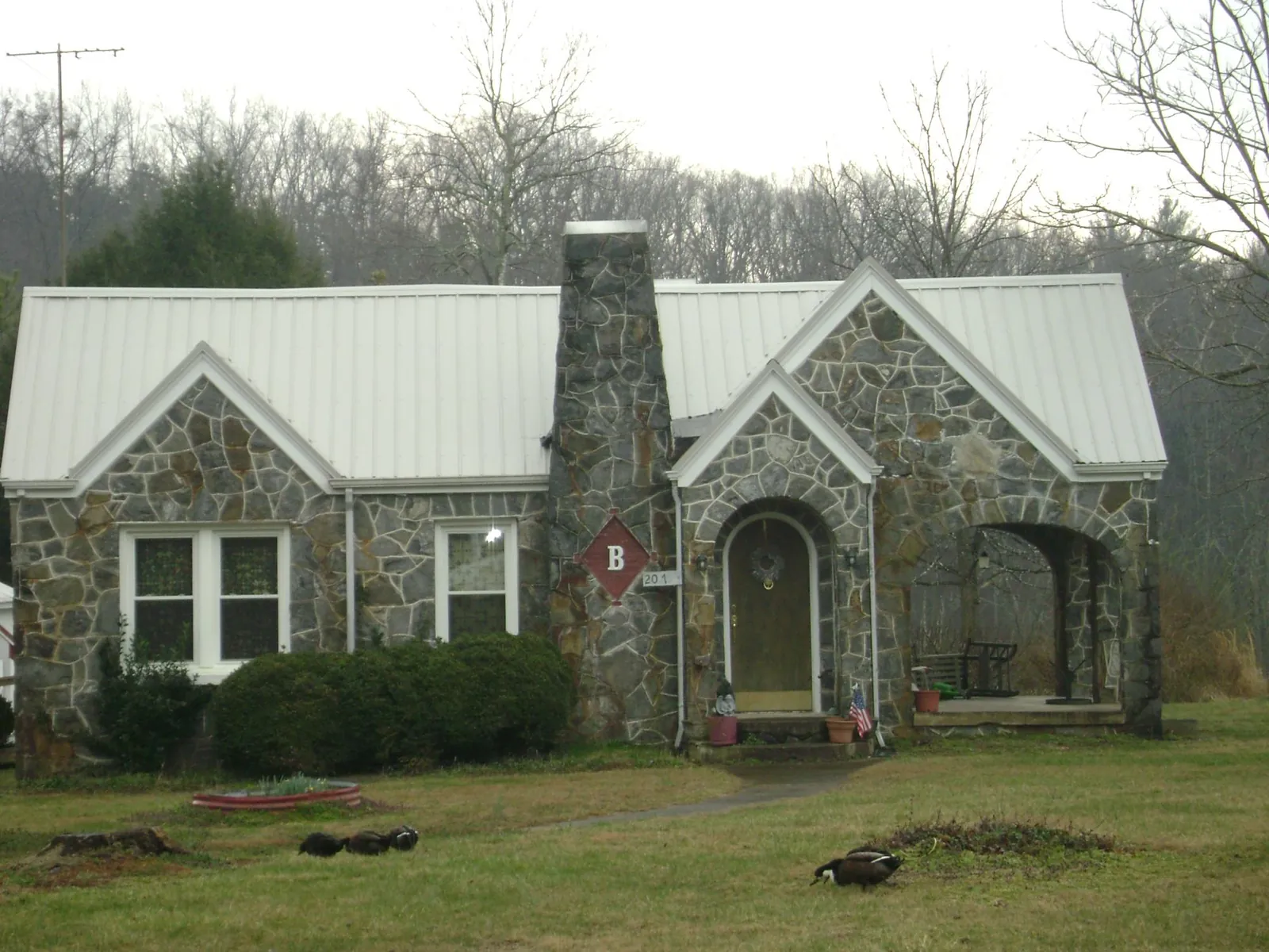 White metal roof on a stone cottage with steep gables in Mercer