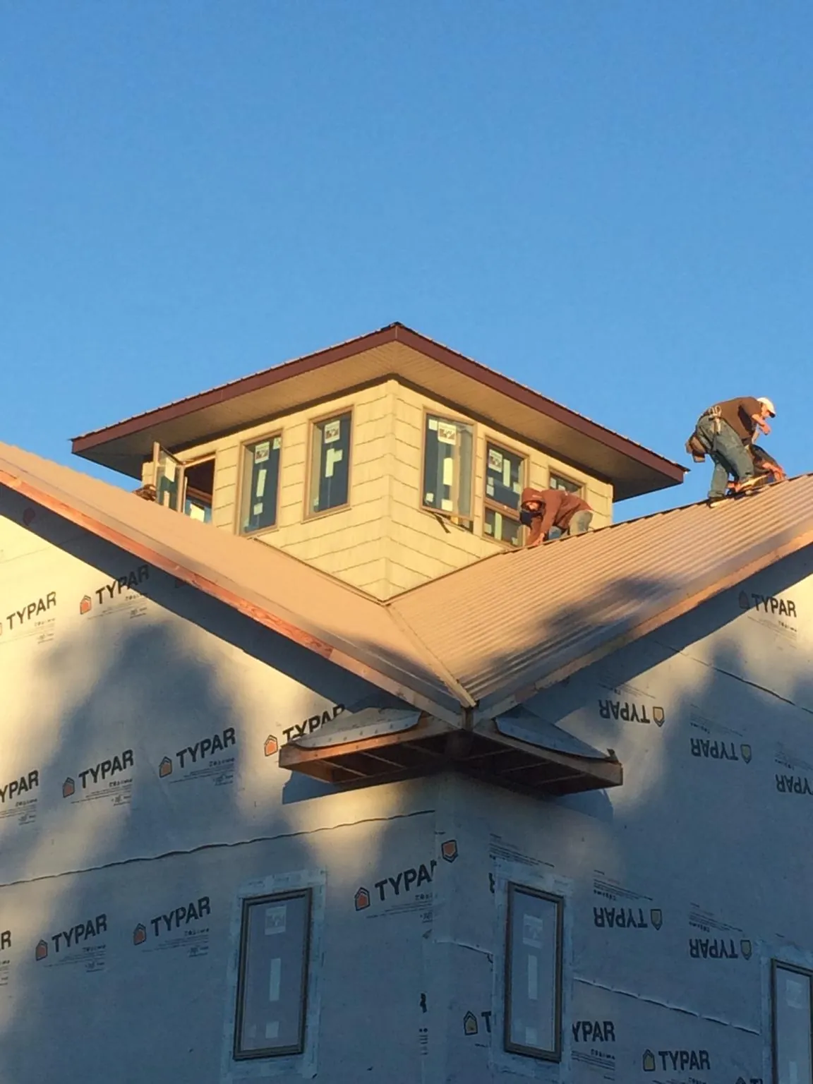 Roofers working around a rooftop cupola on a new metal roof at sunset — Roof Waterproofing in Mercer by Roofing Brothers